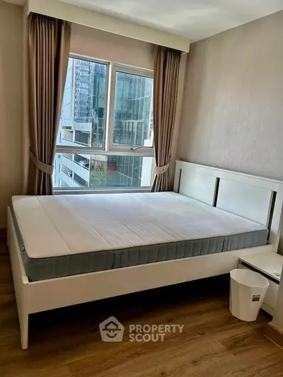 Modern bedroom with large window and city view, featuring a stylish bed and wooden flooring.