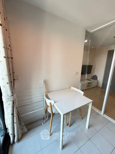 Cozy dining nook with modern table and chairs, adjacent to a bright living area with glass partition.