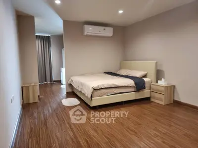 Spacious modern bedroom with wooden flooring and minimalist decor