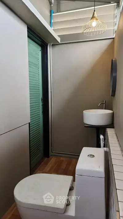 Compact modern bathroom with minimalist design and stylish lighting fixture.