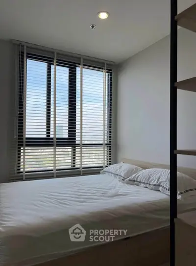 Modern bedroom with large window and stylish blinds offering natural light and serene ambiance.