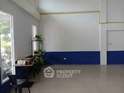 Spacious interior with blue accent wall and large window, ideal for versatile commercial use.