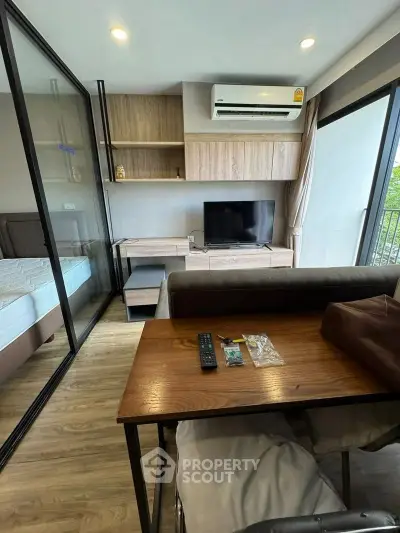 Modern living room with glass partition, cozy sofa, and sleek TV setup in stylish apartment.