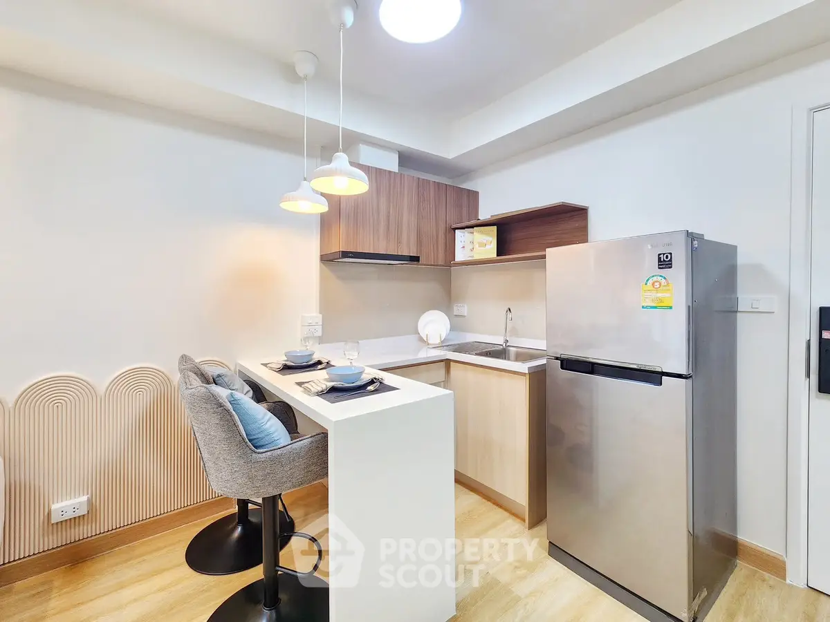 Modern kitchen with sleek design, featuring a breakfast bar and stainless steel fridge.