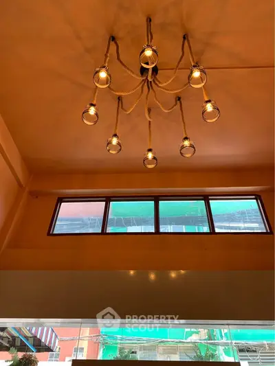 Elegant high ceiling living room with unique chandelier and large windows offering natural light.