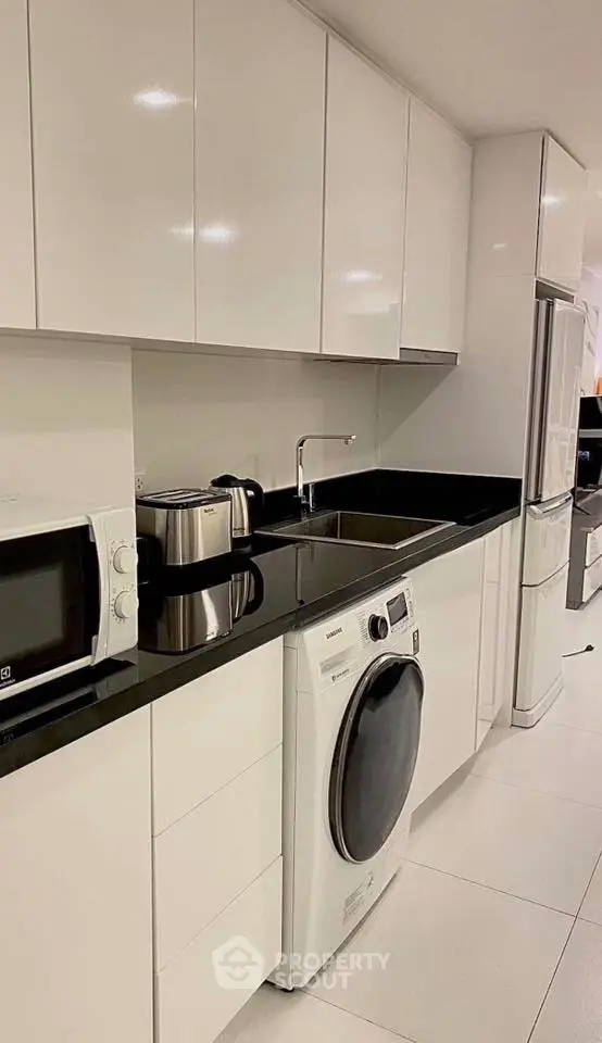 Modern kitchen with sleek white cabinets and built-in appliances.