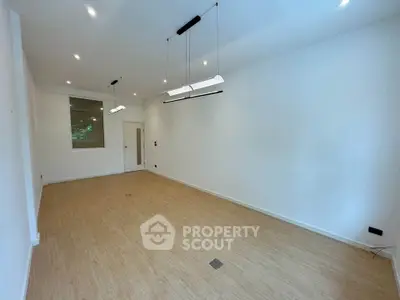 Spacious empty room with modern lighting and wooden flooring, ideal for customization.