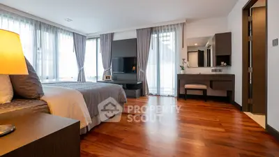 Spacious modern bedroom with wooden flooring and large windows for natural light.