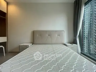 Modern bedroom with large window and stylish headboard in urban apartment.