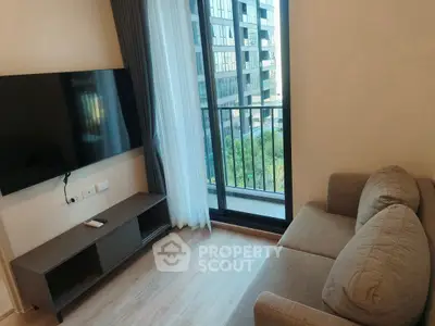 Modern living room with sleek TV and cozy sofa, featuring a balcony view of urban landscape.