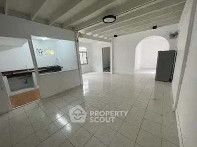Spacious open-plan living area with tiled flooring and natural light.