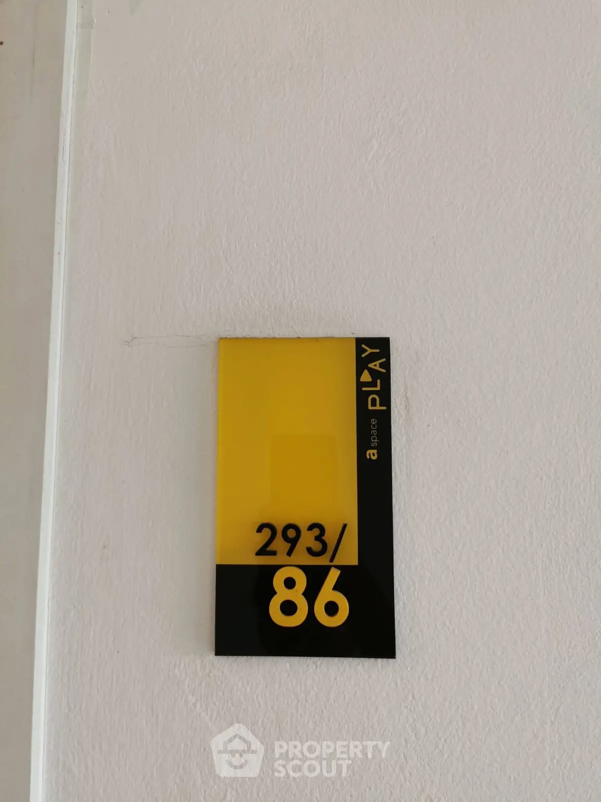Modern apartment number sign with sleek design on white wall.