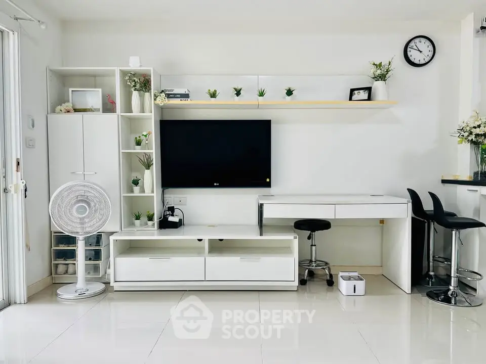 Modern living room with sleek white furniture and wall-mounted TV, perfect for contemporary living.