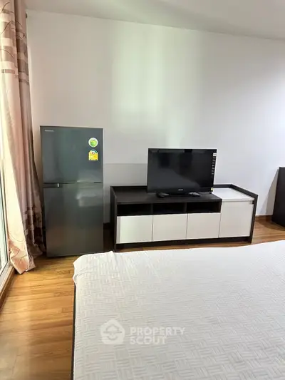 Modern bedroom with sleek TV stand and fridge, perfect for urban living.