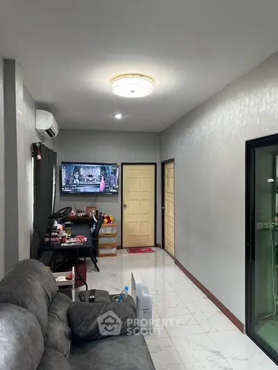 Modern living room with sleek design, featuring a plush sofa, wall-mounted TV, and elegant lighting.