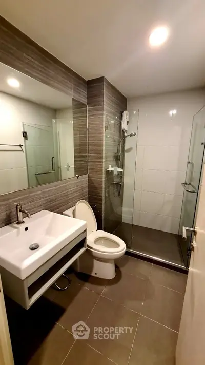 Modern bathroom with glass shower and sleek fixtures in contemporary apartment.