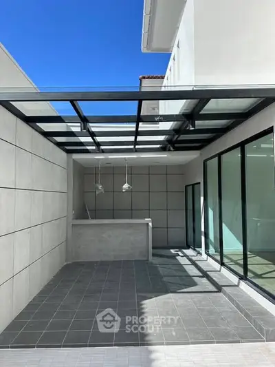 Modern outdoor patio with glass roof and sleek design, perfect for entertaining.