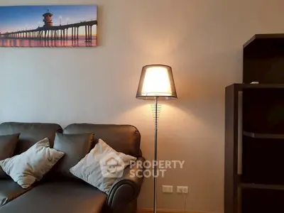 Cozy living room with stylish leather sofa and modern floor lamp, perfect for relaxation.