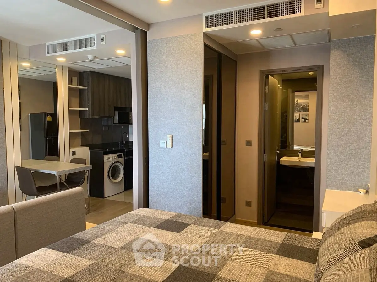 Modern studio apartment with open kitchen and washing machine, featuring stylish decor and cozy living space.
