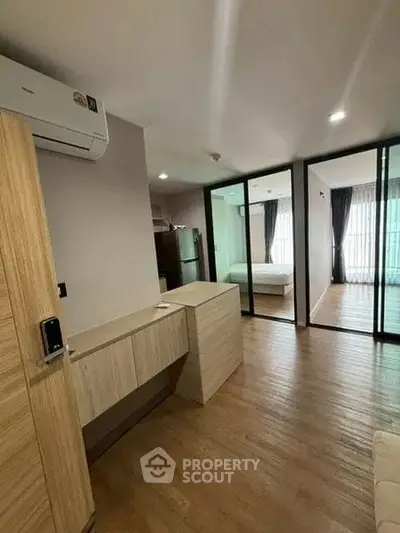Modern apartment interior with wooden flooring and glass partitions, featuring a cozy bedroom and sleek design.