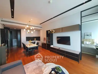 Luxurious modern living room with open kitchen and elegant dining area, featuring sleek design and warm wooden flooring.