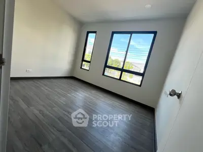 Spacious empty room with large windows and wooden flooring, perfect for customization.