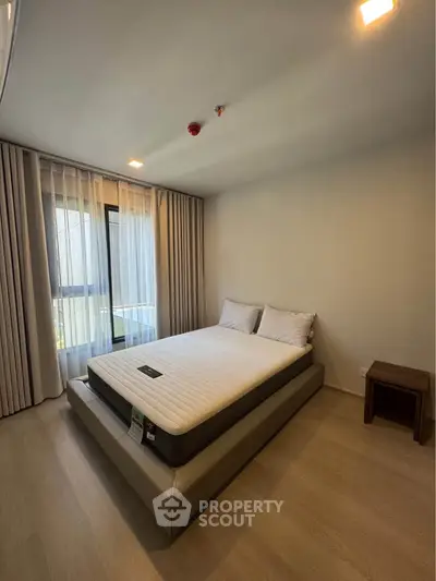 Spacious bedroom with modern decor and large window for natural light