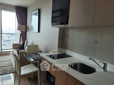 Modern apartment interior with open kitchen and cozy living area, featuring city view from large window.