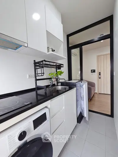 Modern kitchen with sleek appliances and washing machine in compact layout