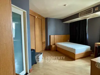 Spacious bedroom with modern wooden furniture and ample natural light.