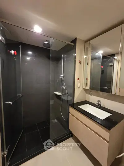 Modern bathroom with sleek glass shower and stylish vanity in contemporary apartment.