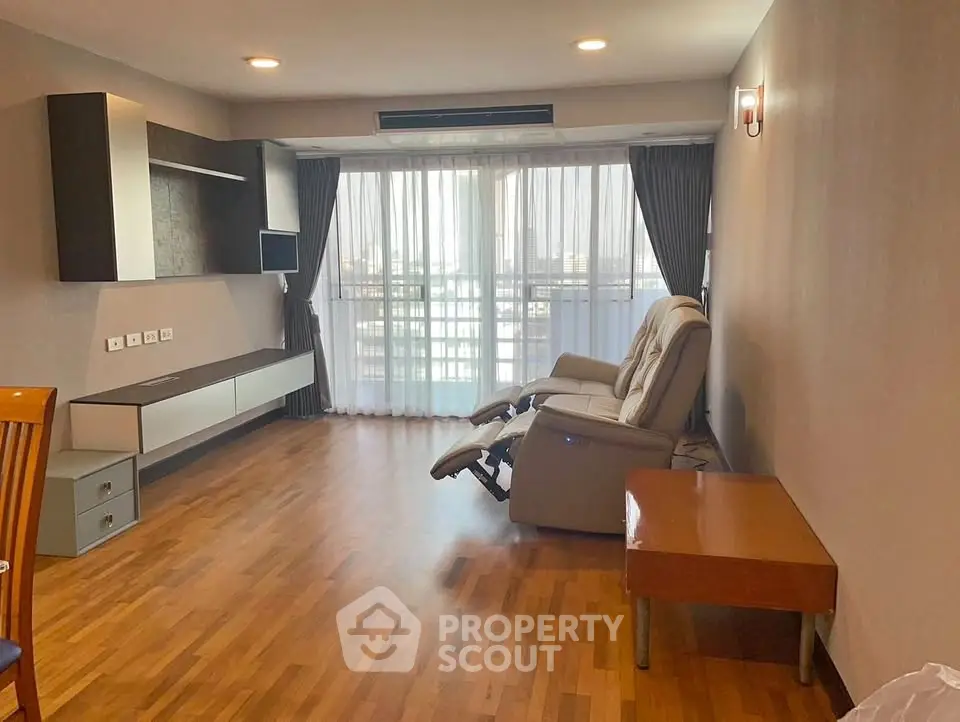 Spacious living room with wooden flooring and modern recliner chair, perfect for relaxation.