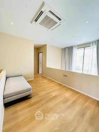 Spacious modern living room with wooden flooring and large window for natural light.