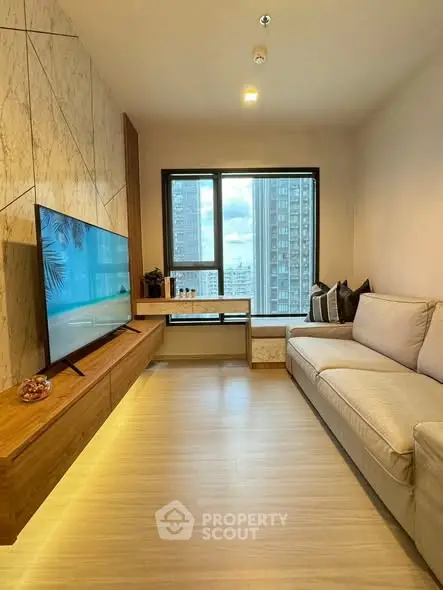 Modern living room with large TV, cozy sofa, and city view window.