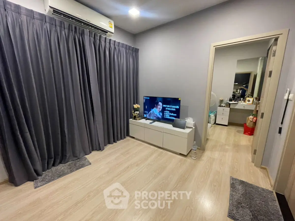 Modern living room with sleek flooring, stylish curtains, and a wall-mounted air conditioner.
