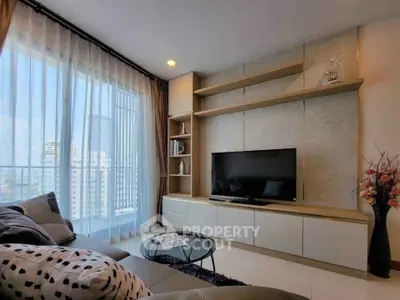 Modern living room with large TV, stylish shelving, and city view through floor-to-ceiling windows.