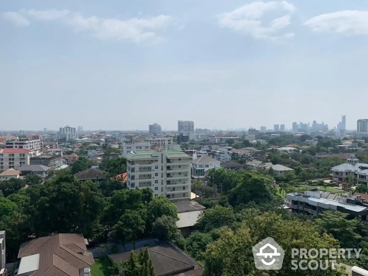 Stunning cityscape view from high-rise apartment overlooking lush greenery and urban skyline.