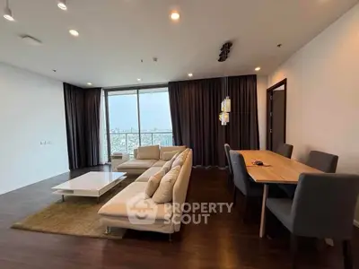 Spacious modern living room with large windows and elegant dining area, offering stunning city views.