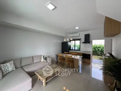 Spacious modern living room with open kitchen and garden view, featuring elegant furniture and ample natural light.