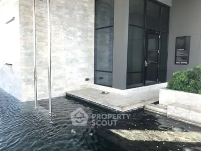 Modern building entrance with sleek water feature and glass facade.