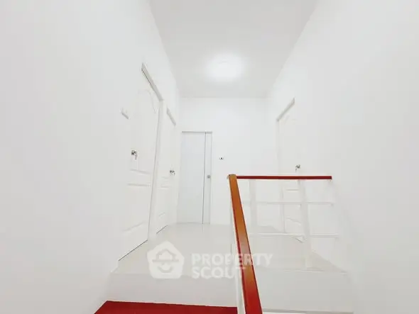 Bright and minimalistic hallway with white doors and staircase, perfect for modern living.