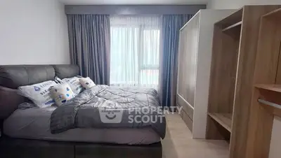 Cozy bedroom with modern furnishings and ample natural light from large window.