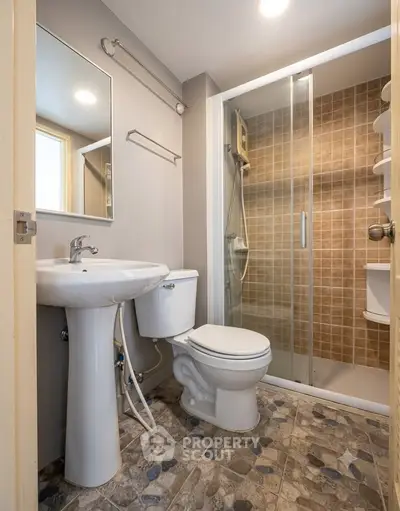 Modern bathroom with shower and stylish tile flooring in a cozy apartment.