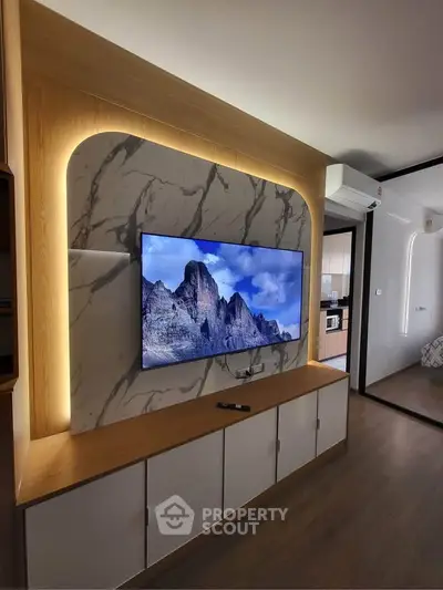 Modern living room with stylish TV wall and sleek cabinetry, featuring a glimpse into a contemporary kitchen.