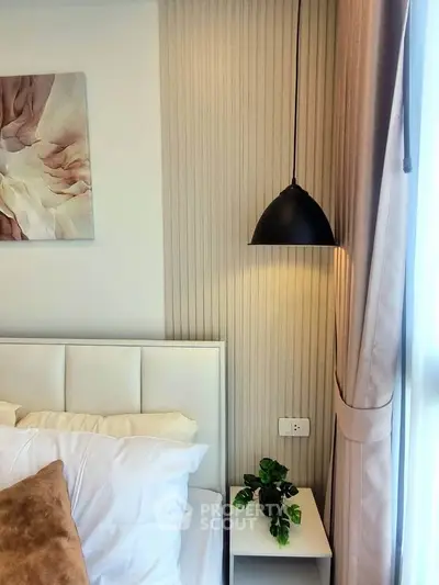 Elegant bedroom corner with modern pendant light and plush bedding, perfect for relaxation.