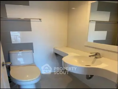 Modern bathroom with sleek fixtures and minimalist design, featuring a stylish sink and toilet.