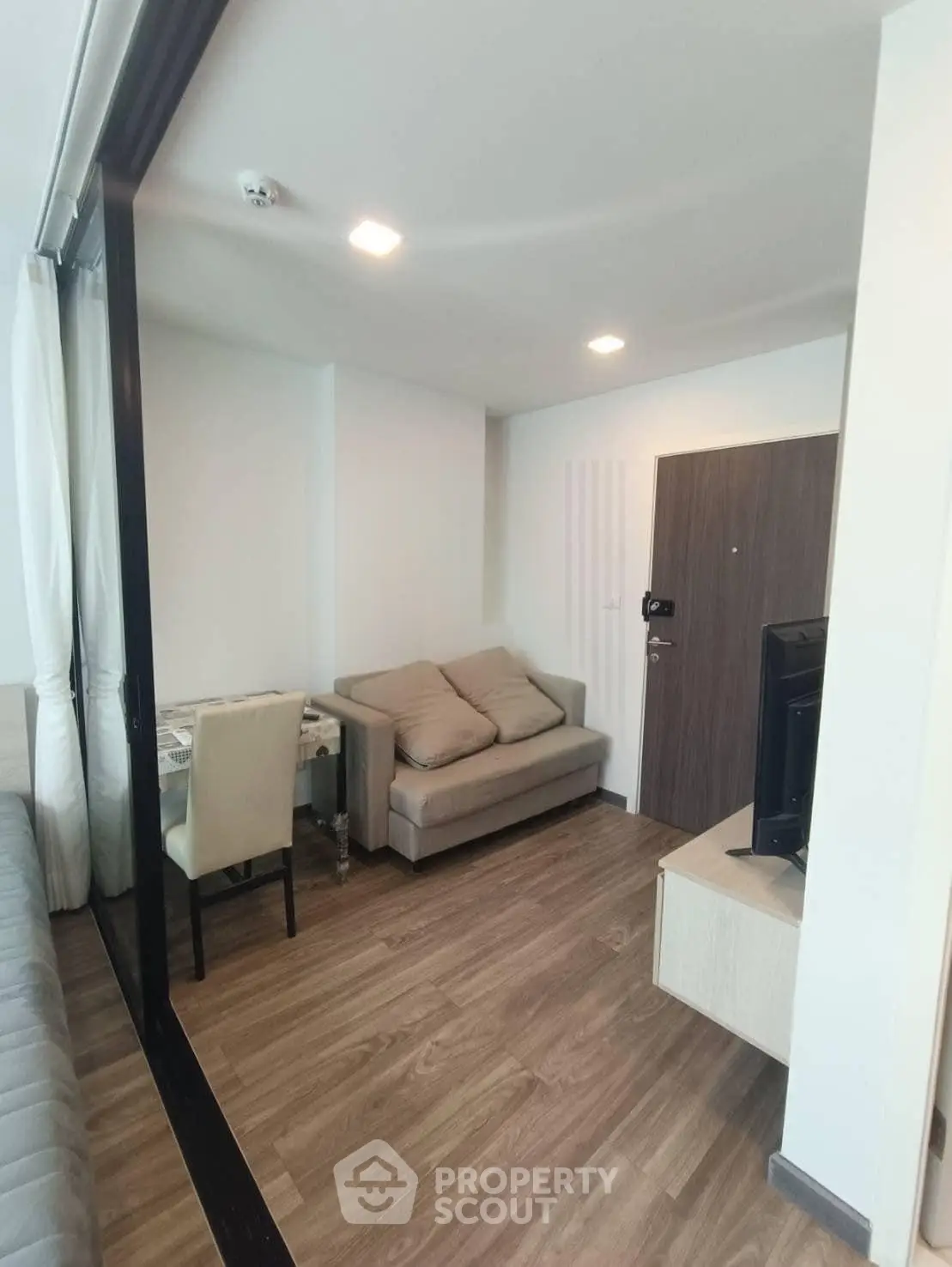 Modern living room with cozy seating and sleek wooden flooring in a stylish apartment.