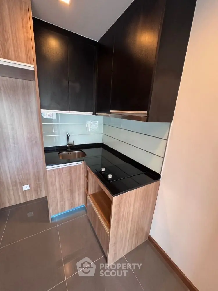 Modern compact kitchen with sleek black countertops and wooden cabinetry