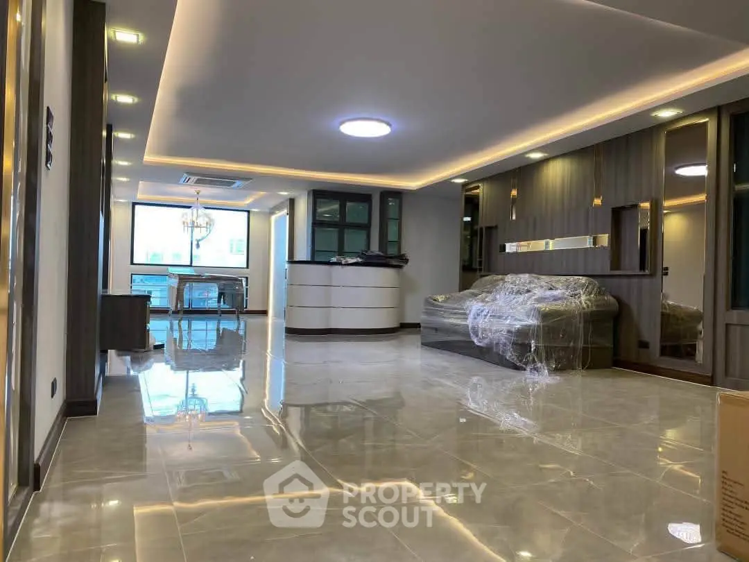 Spacious modern living room with glossy tile flooring and elegant lighting in a luxury apartment.