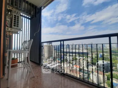 Stunning cityscape view from a modern balcony with seating area.